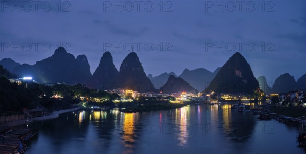 Panorama of Yangshuo town illuminated in the evening with dramatic karst mountain landscape in