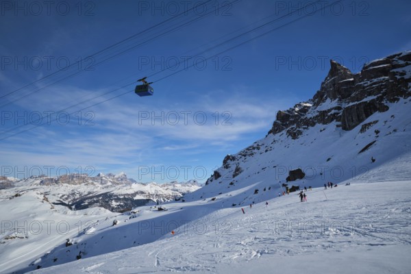View of a ski resort piste with people skiing in Dolomites in Italy with cable car ski lift. Ski