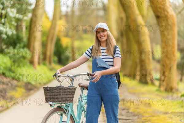 Young woman walking alongside her bicycle in a vibrant park, soaking up the warmth of a sunny day