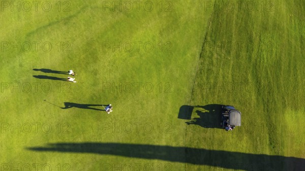Aerial top view of three people on a green luxury gold course