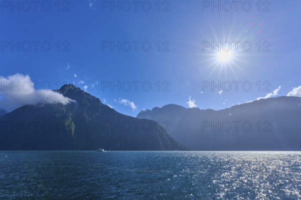 Bright sun over mountains and an expanse of water, summer, Milford Sound, Te Anau, Fiordland