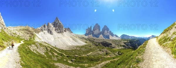 Panoramic. Hikers enjoying a sunny summer day on a scenic mountain trail near the iconic tre cime