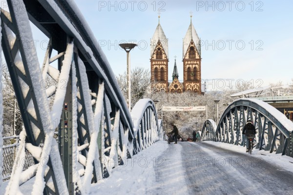 Bridge with snow and ice and cyclists, Blue Bridge and Stühlinger Church, Freiburg im Breisgau,