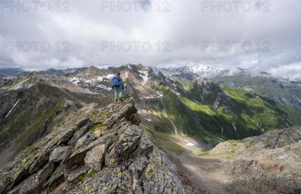 Mountaineer on a steep rocky ridge, on the summit of the Lasörling, view of mountains of the