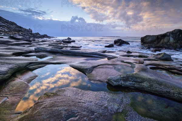 Rocks on beach of fjord of Norwegian sea in winteron sunset. Utakliev beach, Lofoten islands,