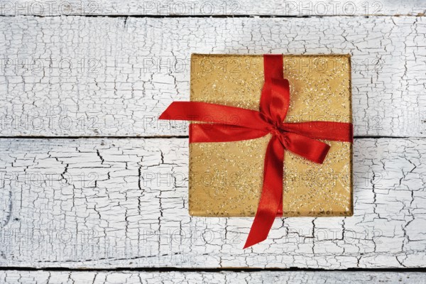 Gift birthday Christmas present concept, yellow gold gift box with red ribbon on white painted