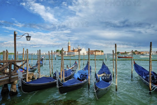 VENICE, ITALY, JUNE 27, 2018: Gondolas and gondolier in lagoon of Venice by Saint Mark (San Marco)