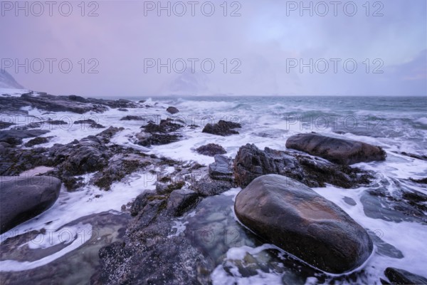 Beach of Norwegian sea on rocky coast in fjord on sunset in winter. Vareid beach, Lofoten islands,