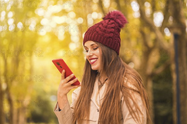 Portrait of a beautiful woman in autumn next to a forest in nature smiling sending a voice note