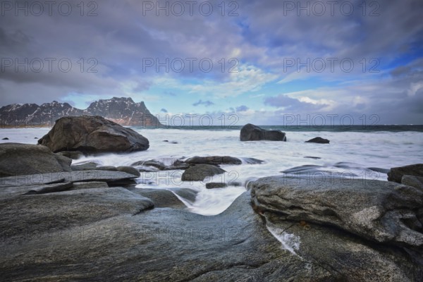 Rocks on beach of fjord of Norwegian sea in winter with snow. Utakliev beach, Lofoten islands,