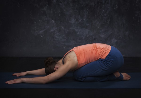 Beautiful sporty fit yogini woman practices yoga asana balasana (child's pose), resting pose or