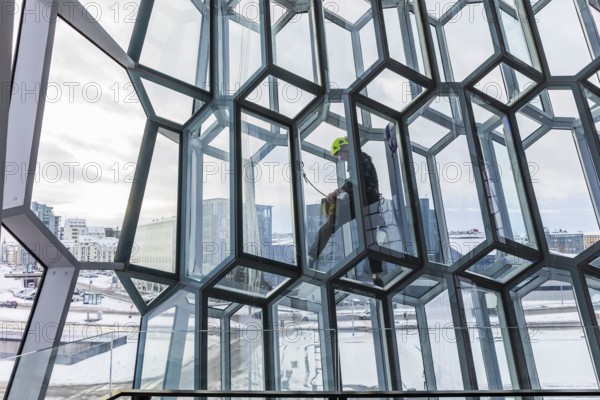 Window cleaners cleaning the glass facade of the Harpa Concert Hall and Congress Centre, interior