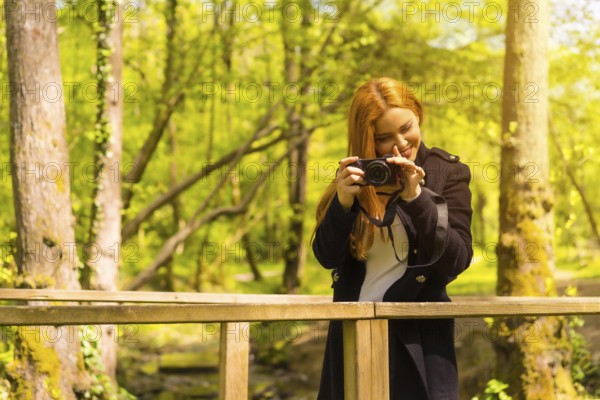 Woman photographer with a black jacket enjoying in an autumn park, smiling and enjoying taking