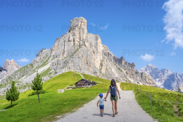 Mother and son walking on a path near the impressive giau pass in the italian dolomites, enjoying