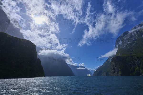 Sunny landscape with mountains and a ship in the distance, summer, Milford Sound, Te Anau,