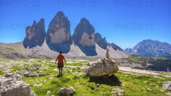 Tourist enjoying the breathtaking view of the tre cime di lavaredo peaks while hiking in the