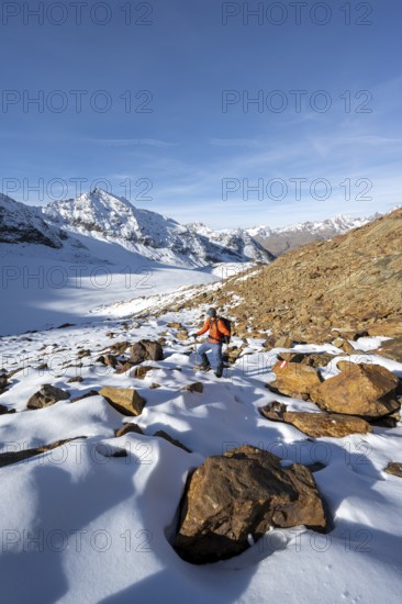 Mountaineer on a hiking trail with snow, descent from Ramoljoch at Spiegelferner, autumnal mountain