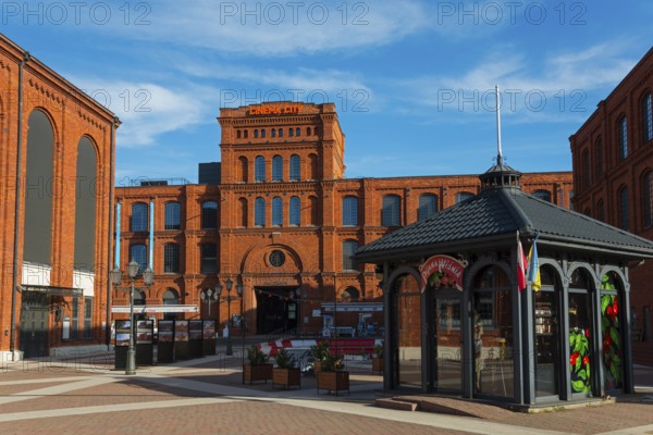 Historic red brick building complex with modern pavilion in an urban setting, Manufaktura, Lódz,