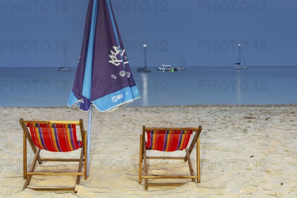Abandoned deckchairs and parasol after sunset at Charlie Beach, Koh Mook Island, Andaman Sea,