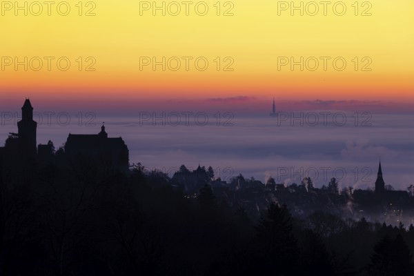 The silhouette of the town of Kronberg im Taunus stands out from the fog and cloud cover that