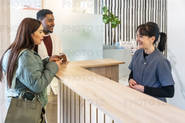 Interracial couple filling out paperwork at the reception desk of a modern dental clinic,