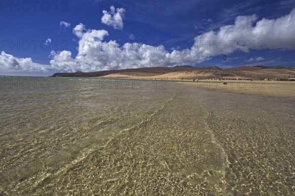 Beach Playa Risco del Paso, Playa de Sotavento with clear water, blue sky and white clouds,