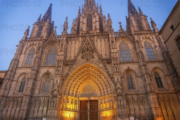 Warm lights illuminating the ornate facade of barcelona cathedral in the gothic quarter at dusk,