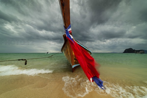 Longtail boat on the beach, dark rain clouds behind, Koh Ngai Island, Andaman Sea, Satun Province,