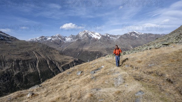 Mountaineers on a hiking trail in Niedertal, snow-covered mountain peaks of the Ötztal Alps with