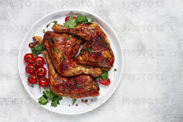 Grilled fried chicken legs, served, with fresh cherry tomatoes, and herbs, on a white plate,