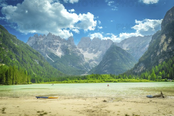 Tourists swimming and paddleboarding in the turquoise waters of lago di landro, surrounded by the