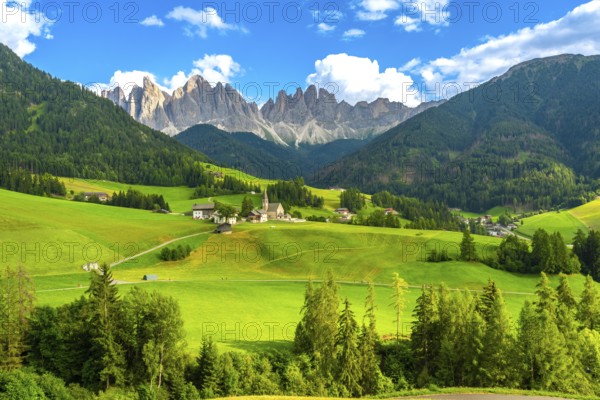 Green meadows blanket the valley in front of santa maddalena village, framed by the stunning odle