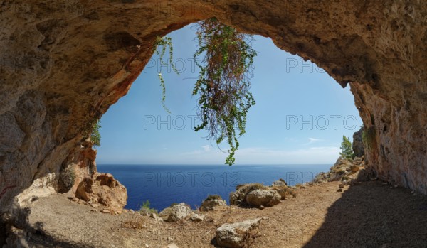 Natural setting of the exit of Limniatis Cave overlooking the sea with rocks and plants, hike from