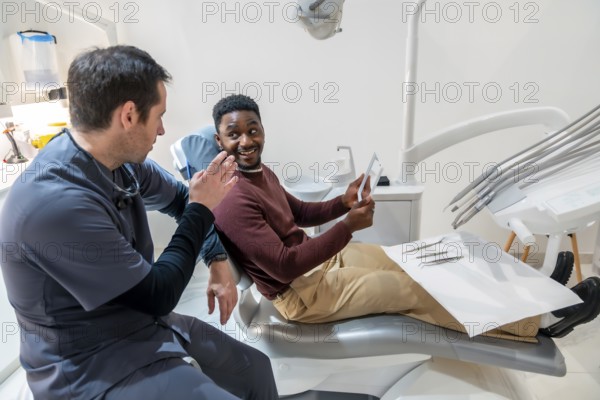 Dentist explaining a dental x ray to a patient sitting in a dental chair, discussing a treatment