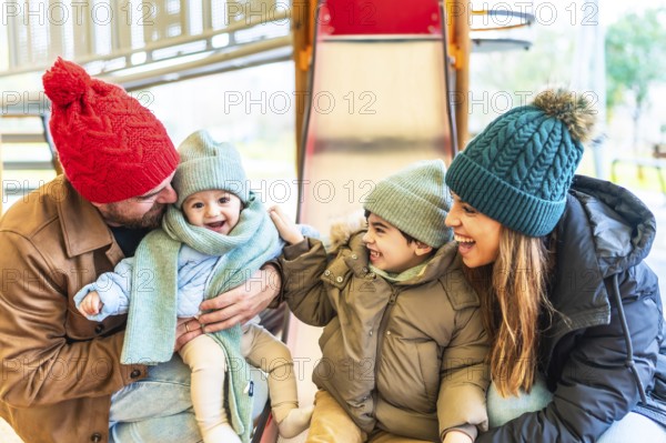 Cheerful family bundled in warm winter clothes, enjoying playful moments together on a playground