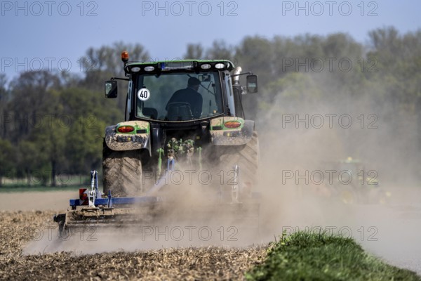 A tractor works a field, due to long dryness in spring, no rain for more than 4 weeks, the fields