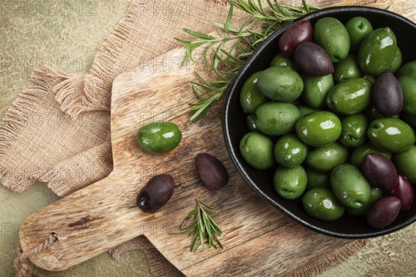 Chalkidiki olives, classic Greek green olives, in a bowl on a cutting board, top view, without