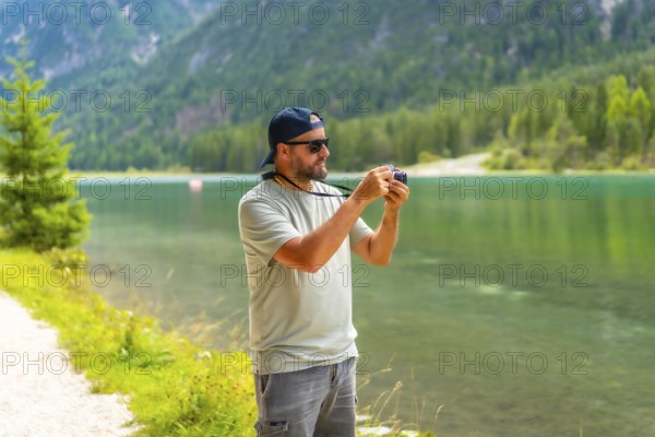 Tourist taking photos of the landscape at lake dobbiaco during summer holidays in the italian
