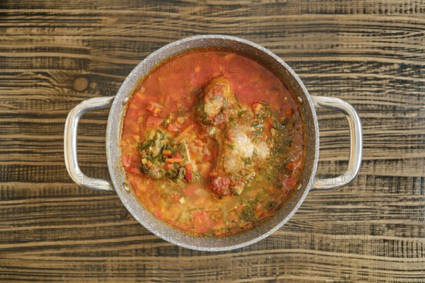 A hearty turkey stew with vibrant vegetables is simmering in a pot on a wooden surface. The rich