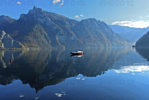 Lonely boat anchored on the mirror-smooth water of Lake Lake Traun, Traunkirchen, Salzkammergut,