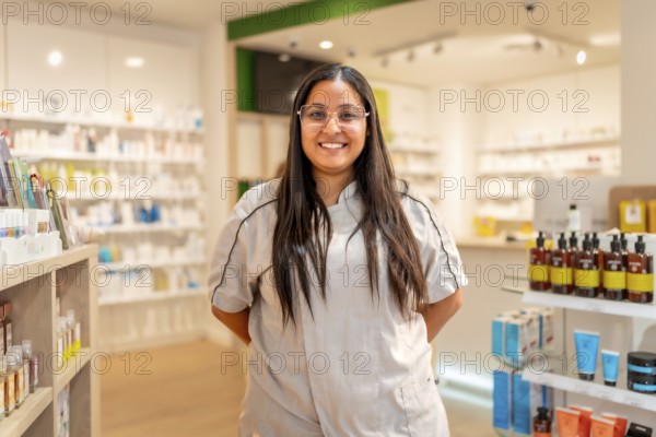 Portrait of a cheerful young female pharmacist with eyeglasses and uniform standing smiling at