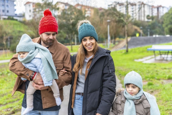 Smiling family enjoying a delightful winter walk in the park, bundled up in warm hats and scarves,