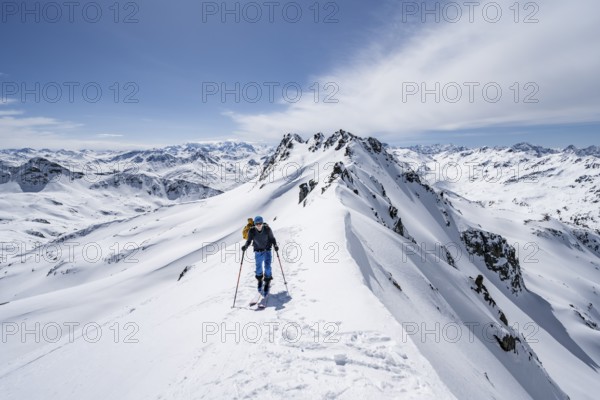 Ski tourer on a mountain ridge, mountain landscape with snow, mountain panorama with summit of the