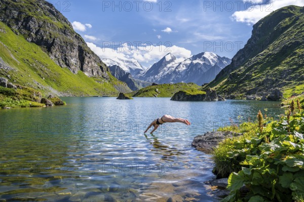 Woman taking a dip, cooling off in the mountain lake Lac de Louvie, behind the summit of the Grand