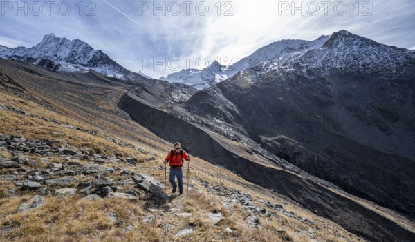 Mountaineers on a hiking trail in Niedertal, snow-covered mountain peaks of the Ötztal Alps with