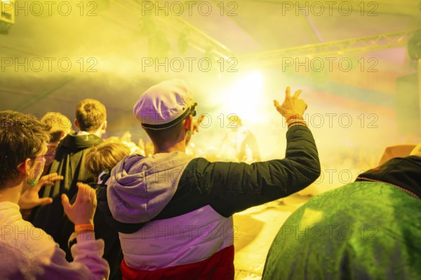Audience enjoys a brightly lit show at an event, the atmosphere is lively and festive, carnival,