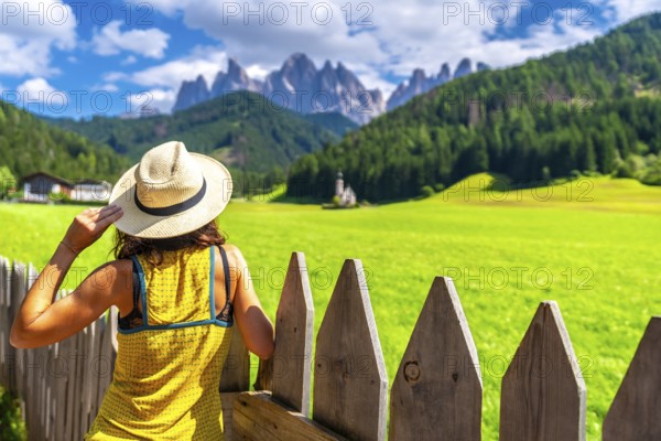 Female tourist wearing a straw hat admiring the stunning view of the odle mountains and st.