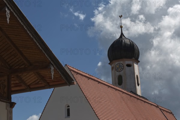 A baroque church tower and part of a roof in front of a blue sky with clouds, Wallgau, Bavaria,