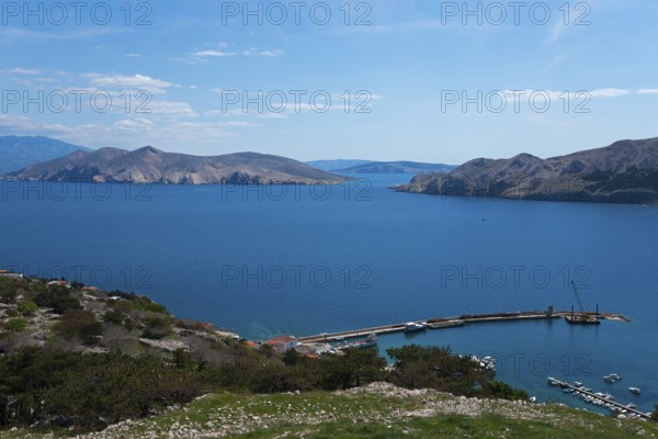 Panoramic view of a harbour on the calm blue sea, surrounded by mountains and islands, view from