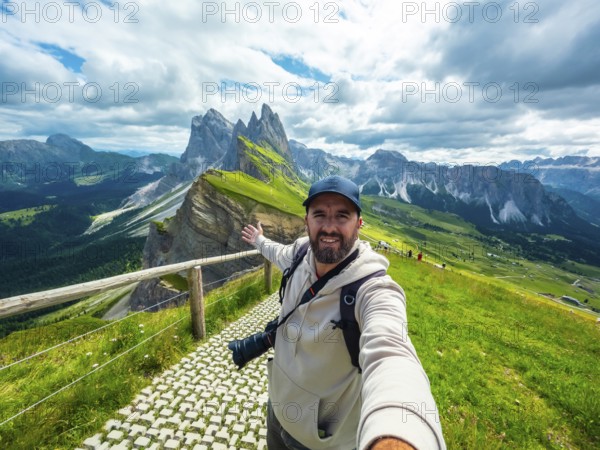 Photographer with backpack and camera taking a selfie with outstretched arm with the odle di eores